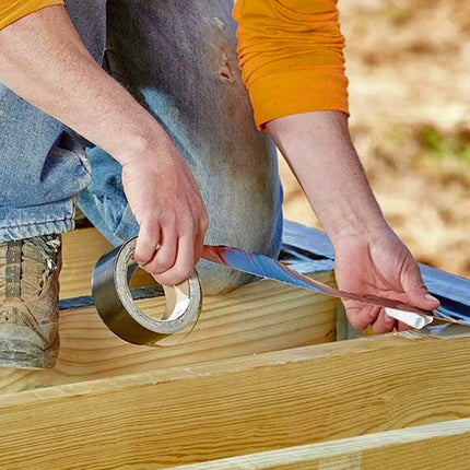 Person applying tape to wooden beams outdoors