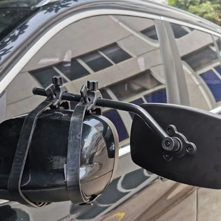 A close-up of a black car side mirror with an attached mounting bracket and strap, shown on the side of a dark vehicle.