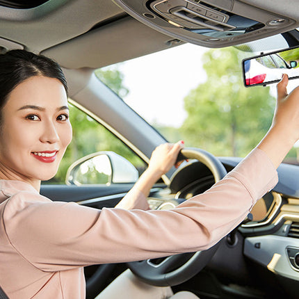 Woman driving a car and checking the rearview mirror.