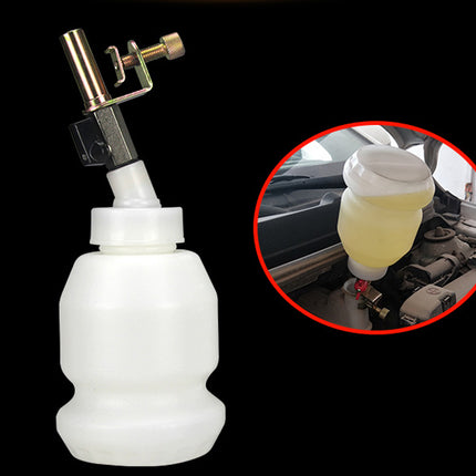 A white plastic bottle with a metal and plastic spray nozzle attachment shown on a black background, with a circular inset demonstrating the bottle connected to a car engine reservoir.