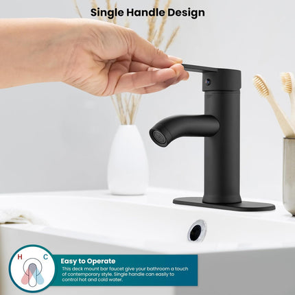 Black single-handle faucet on a bathroom sink with a hand reaching towards it.