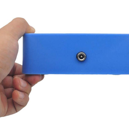 A hand holding a blue rectangular electronic device with a small circular port on the front, shown against a plain white background.