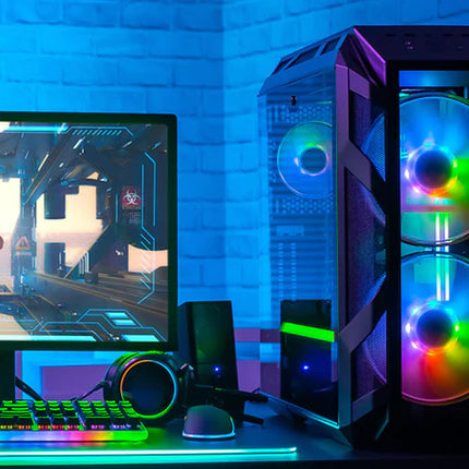 Gaming setup with monitor, keyboard, and RGB-lit computer case on a desk.