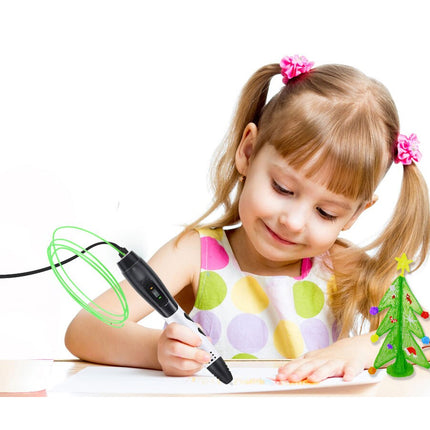 A young girl with blonde pigtails wearing a colorful polka-dot dress is smiling while using a 3D pen to draw on paper. She is surrounded by small toy decorations, including a green Christmas tree and a snowman, on a clean white background.