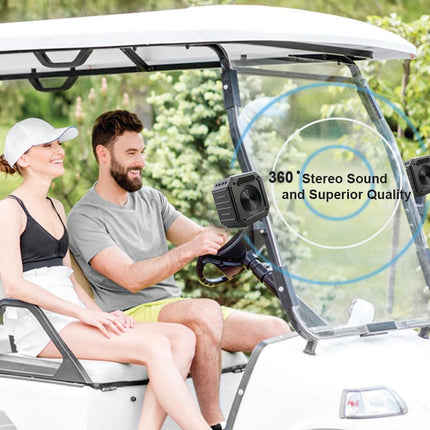 Two people sitting in a golf cart with stereo sound equipment, surrounded by greenery.