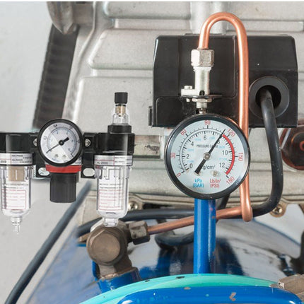 Close-up of an air compressor with pressure gauges and hoses.