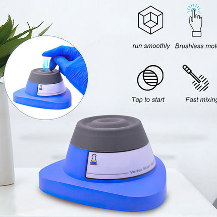 Blue and gray lab mixer with a hand in blue glove using it, on a white surface with greenery.