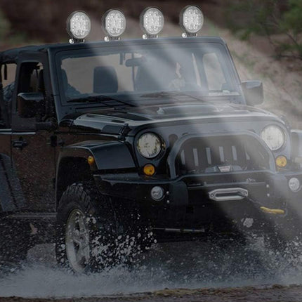 Jeep driving through water with additional lights on