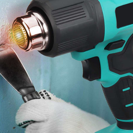 Turquoise heat gun being used on a wall with a white glove holding it.