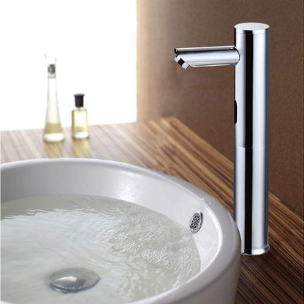 A modern single-handle chrome bathroom faucet mounted beside a white vessel sink on a wood-look countertop, with small bottles blurred in the background.