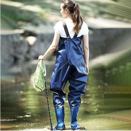 Person wearing blue waders and holding a net by a body of water