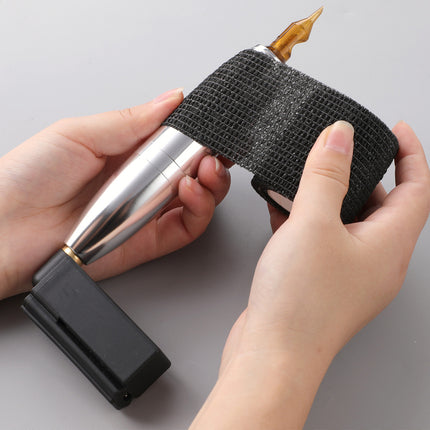 Person holding a black and gold tool with a textured handle on a gray background