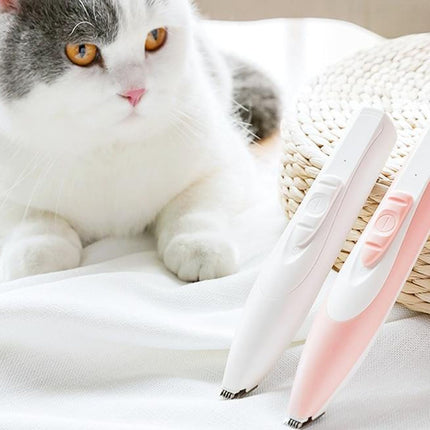 Cat lying next to a white and pink grooming tool on a soft surface