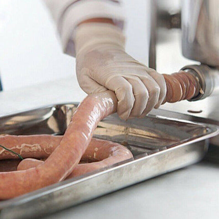 Person handling sausages on a metal tray with a blurred background