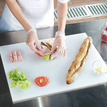 Person making a sandwich on a cutting board with bread, lettuce, and tomato.