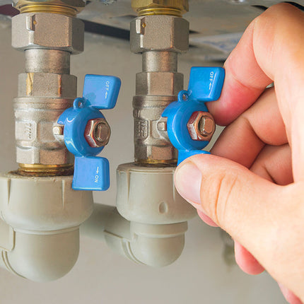 Hand adjusting blue valve handles on a plumbing system.