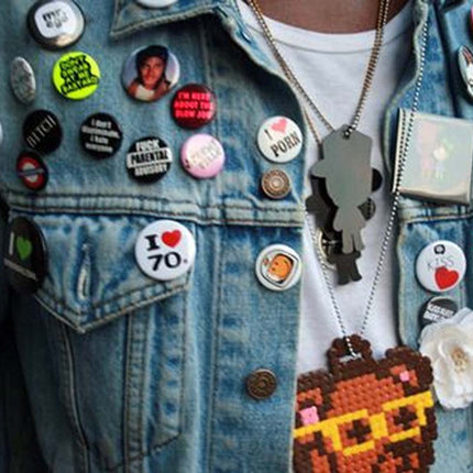 Denim jacket with various buttons and pins worn by a person