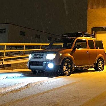 SUV with headlights on in a snowy urban setting at night