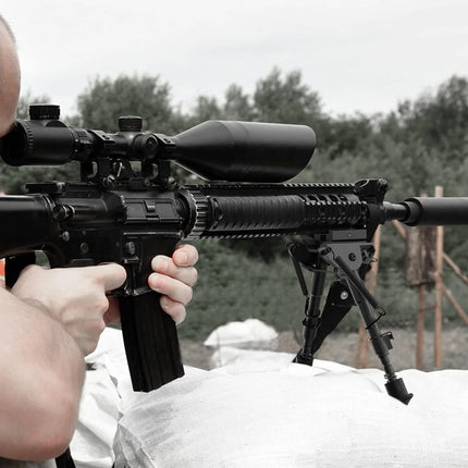 Person holding a rifle with a scope in an outdoor setting