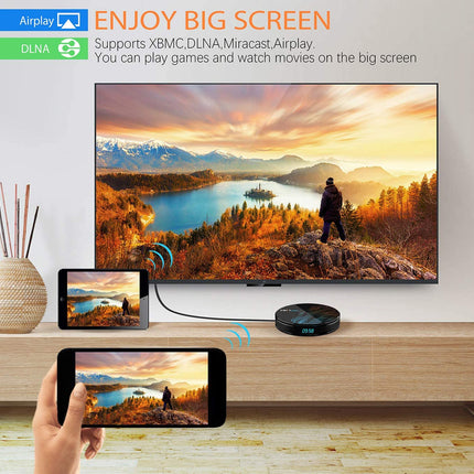 A smart TV on a wooden console displaying a mountain lake landscape, with a black round streaming receiver in front and two smartphones below showing the same content. Text at the top reads 'ENJOY BIG SCREEN' and mentions Airplay and DLNA support.