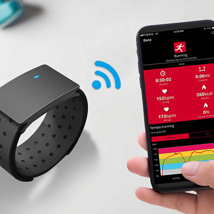 Black fitness tracker and smartphone with fitness app on a white surface