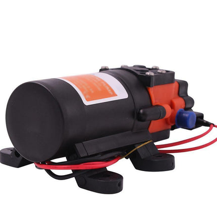 A small electric pump motor with a black cylindrical body, orange and black housing, mounting feet, and attached red and black wires, shown on a plain white background.