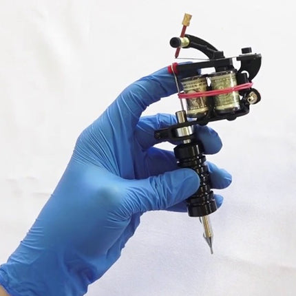 Tattoo machine held by a hand wearing a blue glove on a white background