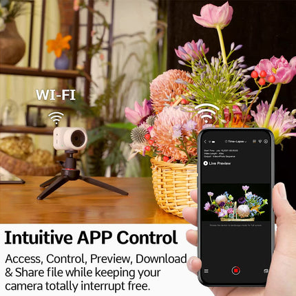 Smart camera on a tripod with a smartphone displaying app controls, placed on a table with flowers in the background.
