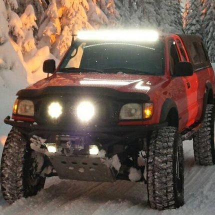 Red pickup truck with large off-road tires in a snowy landscape