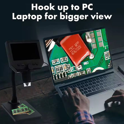 A desktop microscope/laptop combo setup shown on a desk with a person's hands visible, under the text 'Hook up to PC Laptop for bigger view.' The microscope is mounted on a stand and pointed at an open laptop screen displaying a close-up of a green circuit board with a red component.