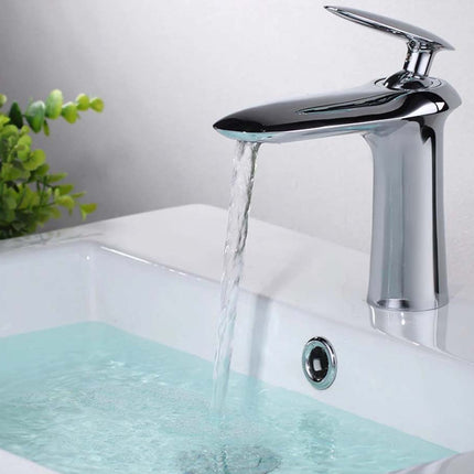 A modern chrome single-handle bathroom faucet with water flowing from the spout into a white sink basin.