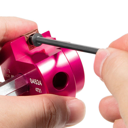 Close-up of a pink metal component being held by hands against a white background