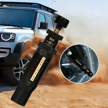 A black tire pressure gauge with a textured grip and gold accents, shown in front of a silver SUV kicking up dust. A circular inset shows a close-up of the gauge tip inserted into a tire.