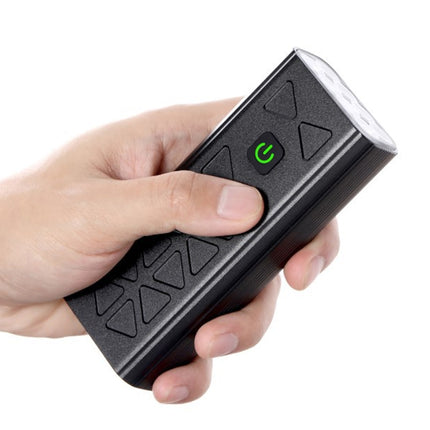 Hand holding a black electronic device with a green power indicator on a white background