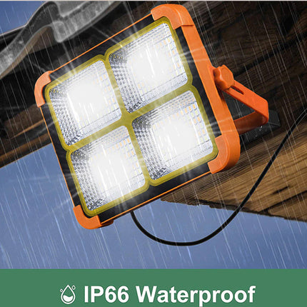 Orange work light with four LED panels on a wooden surface, rain droplets visible, IP66 waterproof label.
