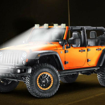 Orange Jeep Wrangler with additional lights on a dark background