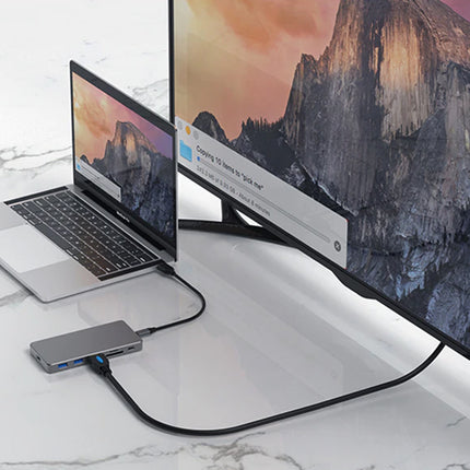 Laptop connected to a monitor via a USB hub on a marble surface