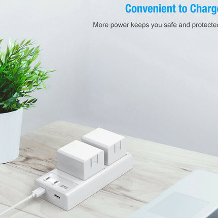 White power strip with multiple outlets and USB ports on a wooden surface with a plant in the background.