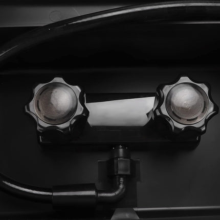Close-up of a black double-head spotlight fixture with two star-shaped side knobs and a central reflective lens, mounted on a dark surface with a hose connected below.