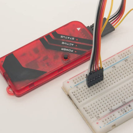 A red translucent electronic module with black printed labels and attached multicolored wires, shown next to a white breadboard on a plain white background.