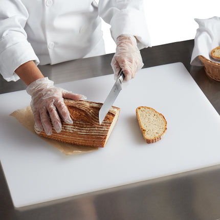 Person slicing bread on a white cutting board with a knife