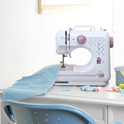 White sewing machine on a table with blue fabric and spools of thread.