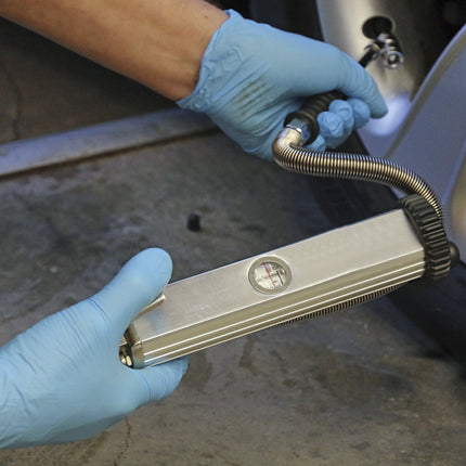 Person using a tire pressure gauge on a car tire with a blurred background