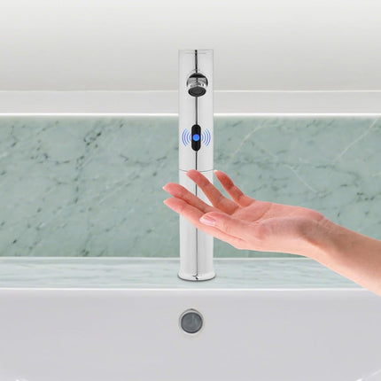 A modern chrome bathroom faucet with a touch sensor and blue LED indicator, shown with a hand reaching toward it in front of a white sink and green marble backsplash.