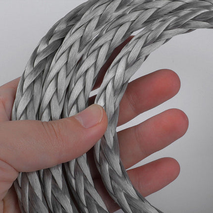 Hand holding a coiled piece of metal cable against a white background