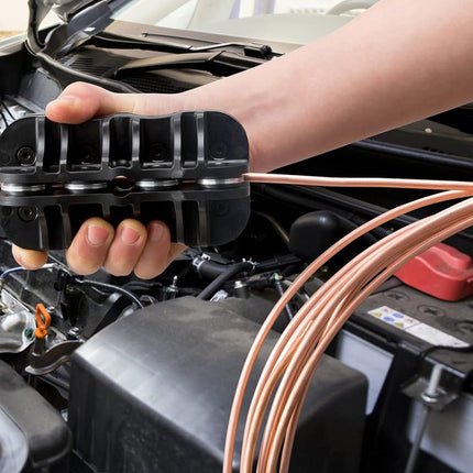Person working on car engine with a black tool and copper wires