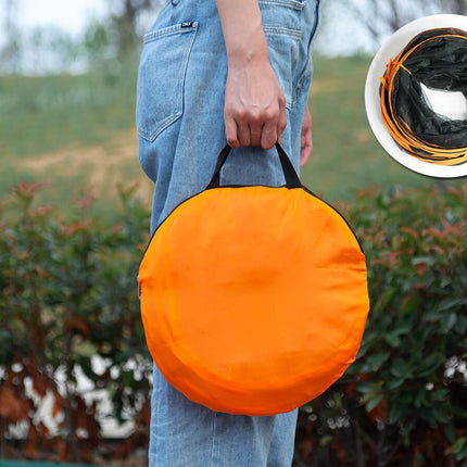 A person outdoors holding a round orange bag with black handles, with a white inset showing the bag folded and filled with orange cords.