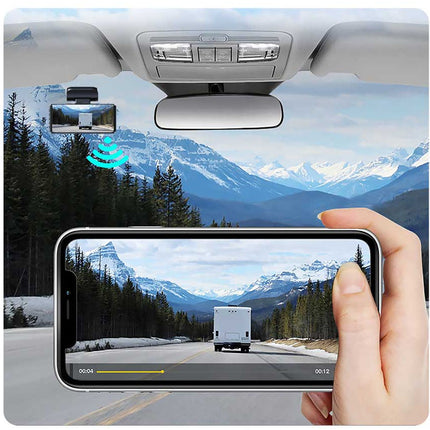 Car rearview mirror with mounted camera and phone displaying a scenic view.