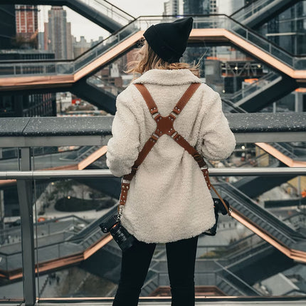 Person wearing a white shearling jacket and black beanie standing on a modern architectural structure.