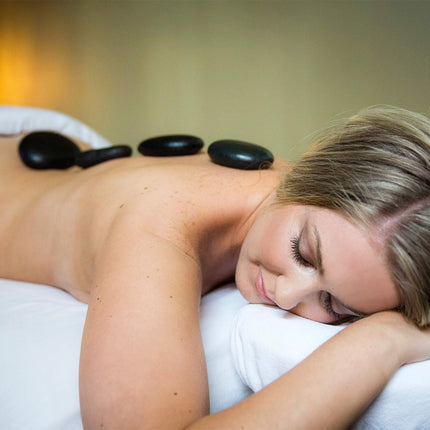 Woman receiving a hot stone massage with a warm ambiance.
